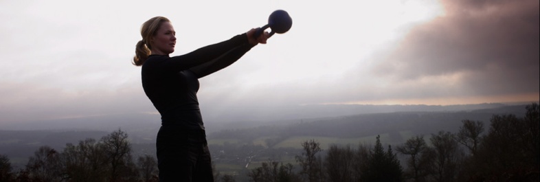 thuis een sixpack trainen met kettlebells, vrouw in natuur met kettlebell