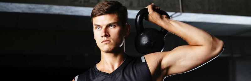 thuis sporten met gewichten, man die kettlebell over zijn schouder vast heeft